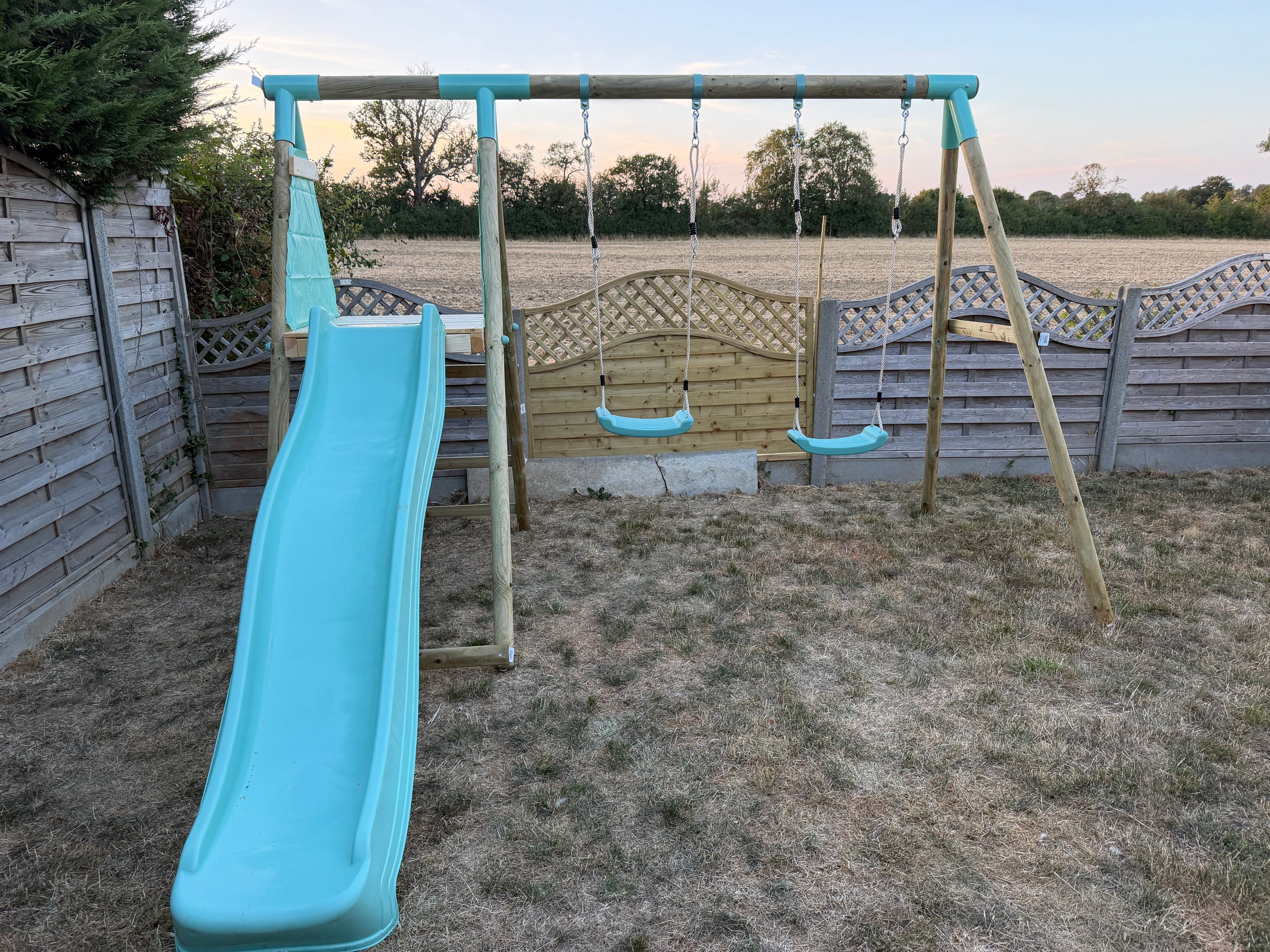 Garden climbing frame with swings and slide assembled on lawn