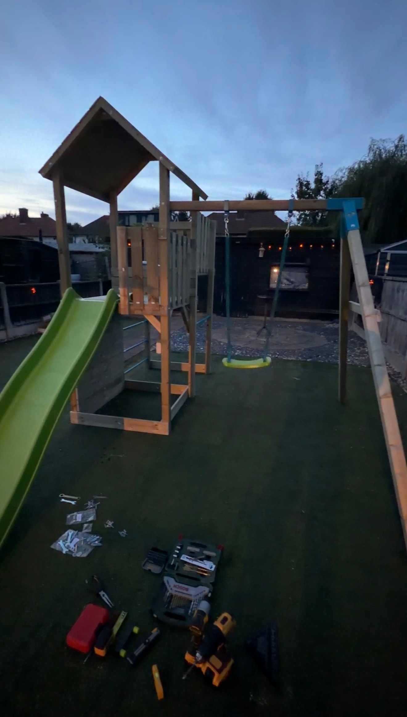 Teal wooden swing set with double swings and matching slide assembled in garden